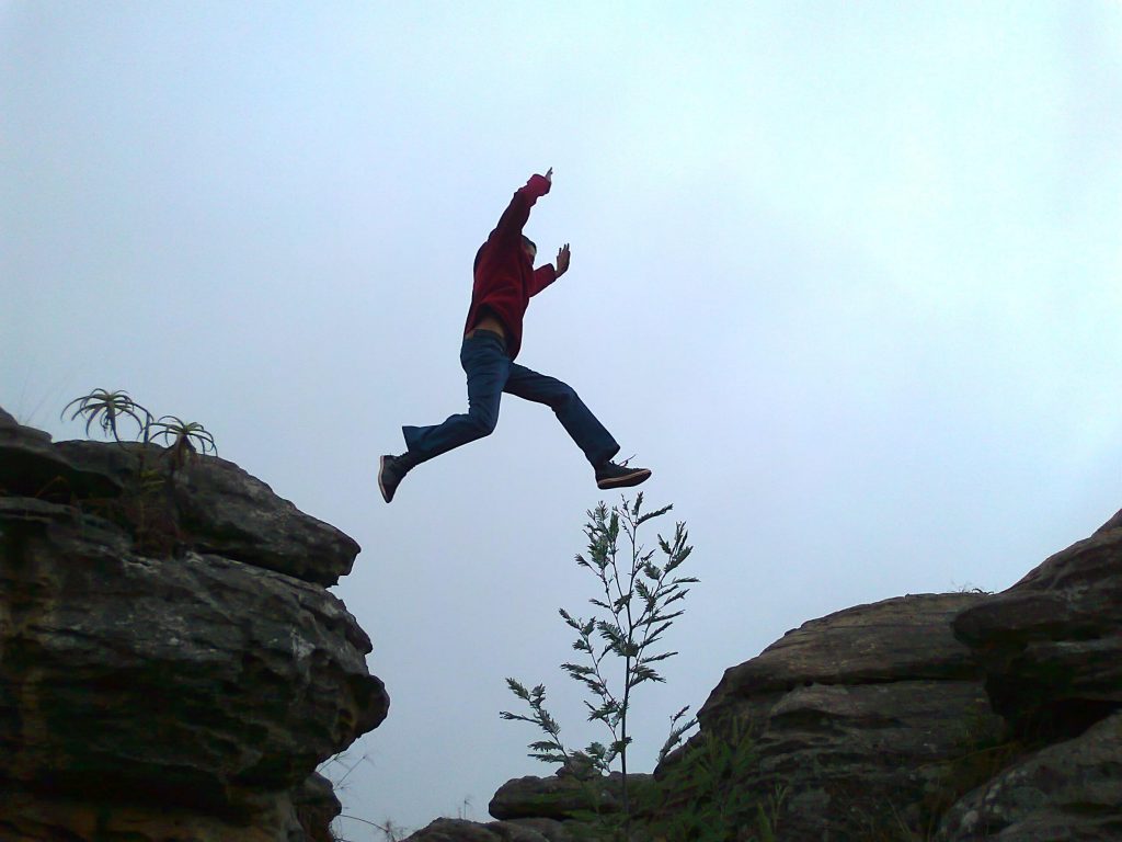 person leaping from rock